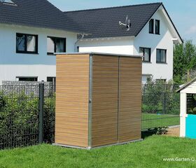 . Ein moderner Gartenschrank aus Holz mit einem weißen Wohnhaus und einem kleinen Spielhaus im Hintergrund.