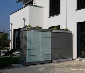 . Ein Gartenschrank steht neben einem modernen weißen Gebäude mit großen Fenstern und Pflanzen auf dem Dach.
