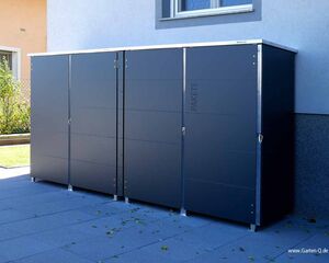 Ein anthrazitfarbener Paketkasten steht vor einem Haus.