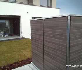 . Ein moderner Gartenschrank neben einem Haus mit Garten und Terrasse, www.garten-q.de sichtbar.