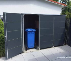 . Ein geöffneter Metallschuppen im Garten mit einer blauen Mülltonne darin.