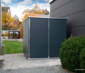 . Ein moderner Gartenunterstand neben einem Gebäude mit Herbstlaub im Hintergrund.