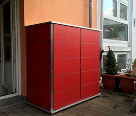 . Ein roter Garten- oder Geräteschrank auf einer Terrasse neben einem Gebäude.