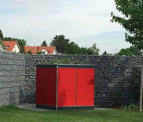 . Ein roter Gartencontainer steht auf einer grünen Rasenfläche, umgeben von einem Steingabionen-Zaun.