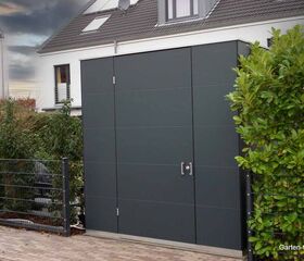 Ein modernes Gartenhaus neben einem Wohnhaus, umgeben von Hecken und einem Zaun.