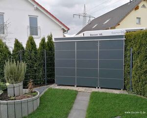 Ein modernes Gartengerätelager im Garten neben einem Haus, umgeben von Rasen und Hecken.