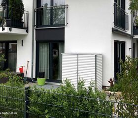 Ein Balkon mit Pflanzen, ein Gartenhäuschen, Pflanzen, Zaun und Gartenwerkzeuge.