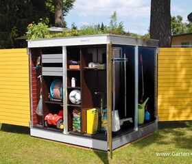 . Ein geöffneter Geräteschuppen mit Gartenwerkzeugen, Schlauch, Ball, Düngemittel und Kinderspielzeug.