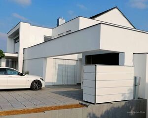 . Modernes weißes Haus mit flachem Dach und einem weißen Auto vor der Garage.