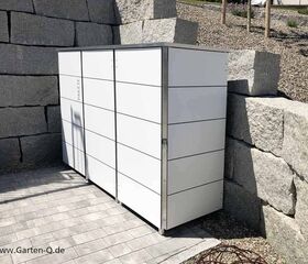 Ein weißer Gartenschrank neben einer Steinmauer. Webadresse: www.Garten-Q.de.