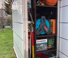 . Ein geöffneter Gartenschrank mit Gartenwerkzeugen, Schlauch, Basketball, und Grillzubehör.
