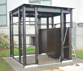 Metallrahmen eines kleinen Schuppen oder Gebäudes im Bauprozess, mit Werkzeug darin auf Fliesenboden.