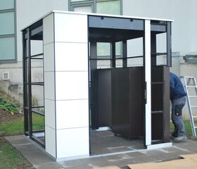 Ein Mann montiert einen schwarzen und weißen Pavillon oder Kiosk, mit einer Leiter im Hintergrund.