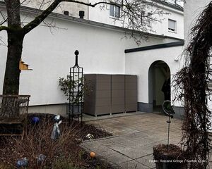 Ein Garten mit Vogelhaus, Bank, braunem Schrank, Pflanzengitter und Dekofiguren.