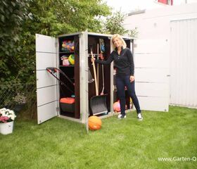 . Frau öffnet einen Gartenschrank mit Bällen, Gartenwerkzeugen und anderen Utensilien im Garten.