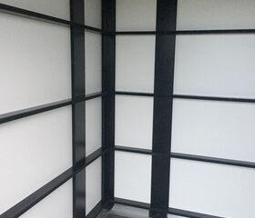 Ein leerer Raum mit schwarzen Rahmen an den Wänden und grauem Fliesenboden.