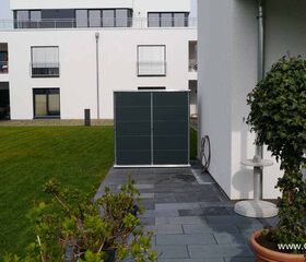 . Moderne Wohnanlage mit Rasen, Terrasse, Pflanzen und einem Gartenmöbelset.