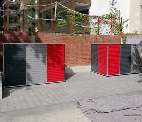 . Zwei Gartenschränke mit roten und grauen Türen stehen auf gepflastertem Boden vor einer Backsteinmauer.