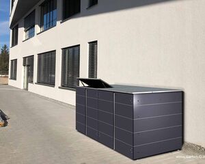 Großer Abfalleimer neben einem modernen Gebäude auf einer gepflasterten Fläche.