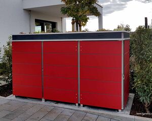 Ein rotes Gartenhaus aus Metall, umgeben von Pflanzen, vor einem modernen Gebäude.
