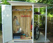Ein offener Geräteschuppen mit Gartengeräten, Regalen und einem Fahrrad.