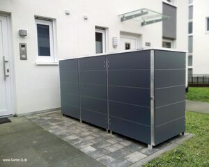 . Ein moderner Gartenhaus-Container neben einem Gebäude mit Pflastersteinen und Rasen.