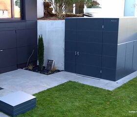 Ein moderner Gartenlagerraum neben einem Gebäude, umgeben von einer Grünfläche und Pflanzen.