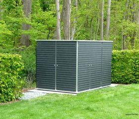 . Ein moderner, grauer Gartenschuppen steht auf einer Wiese, umgeben von Hecken und Bäumen im Hintergrund.