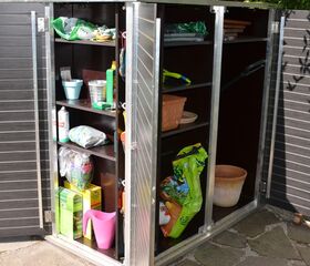 . Ein geöffneter Schrank mit Gartenzubehör: Dünger, Töpfe, Gießkanne, Sprühflasche, Handschuhe, Pflanzenerde.