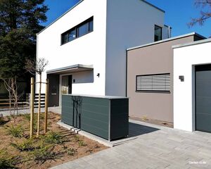 Modernes Haus mit flacher Architektur, Vorgarten mit Pflanzungen und Baum, graue Garage.