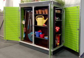 . Ein geöffneter Gartenschrank mit Gartengeräten, Töpfen, Gießkanne, Spielzeug und Pflanzen darauf.