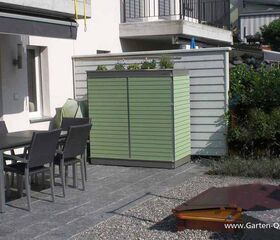 . Ein Gartenmöbel-Set auf einer Terrasse mit grünem Schrank, Pflanzen und überwiegend moderner Umgebung.