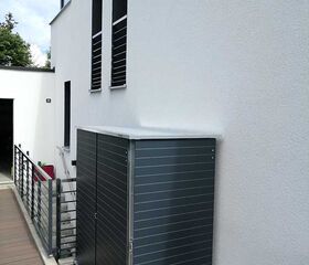 . Metallschrank auf einer Terrasse neben einem modernen weißen Gebäude.