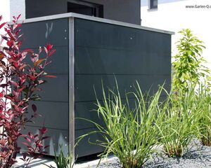 . Ein moderner Gartenschrank umgeben von verschiedenen Pflanzen und Kieselsteinen im Außenbereich.