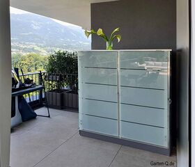 Ein Balkon mit Blick auf die Berge, Pflanze auf Kasten, Gartenmöbel, Geländer und Topfpflanzen.